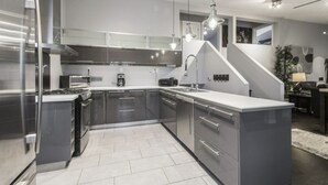 A modern kitchen with stainless steel appliances, grey cabinetry, and a central island. - Executive / Family Home | 2 BR • Office • Parking • 10mins to Toronto or Pearson (Mississauga)