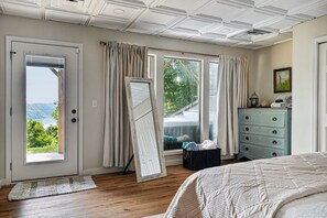 Une chambre avec un grand lit, une commode et une vue sur l’extérieur.