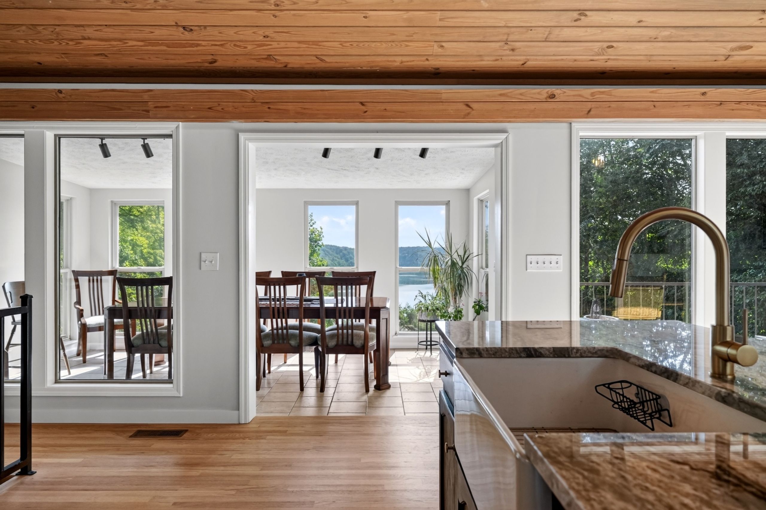 A spacious kitchen with a large island, wooden flooring, and a view of the outdoors.