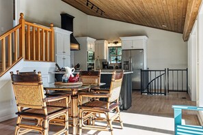 Une cuisine spacieuse avec un coin repas, un escalier en bois et une vue sur l’extérieur.