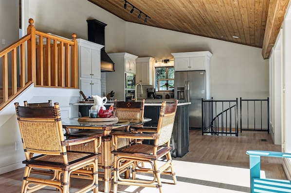 A spacious kitchen with a dining area, wooden staircase, and a view of the outdoors.