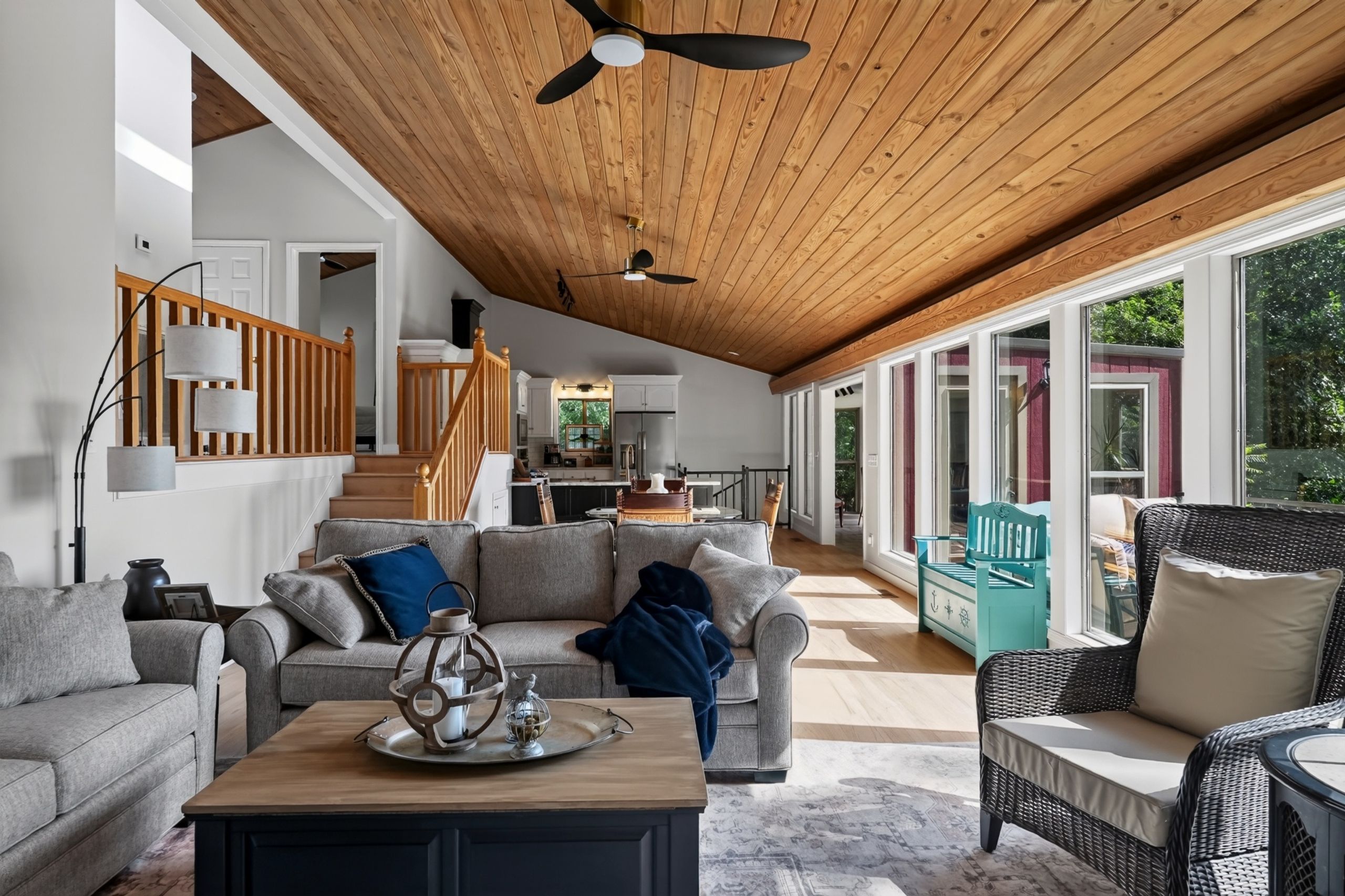 A spacious living area with a high ceiling, wooden beams, and a view of the outdoors through large windows.
