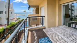 En balkon med udsigt over havet, et træbord og et gelænder.