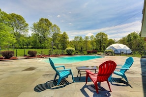A swimming pool with a tiled deck, surrounded by green trees and a white dome structure. - Cozy 2-bedroom mobile home with Pool, AC in lovely Gardiner (Gardiner)