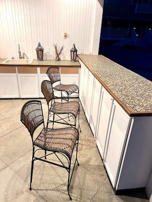 A kitchen with a long counter, white cabinets, and wicker chairs. - Cozy 2-bedroom mobile home with Pool, AC in lovely Gardiner (Gardiner)