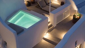 Ett modernt utomhusområde med pool, bubbelbad, bekväma sittplatser och krukväxter.