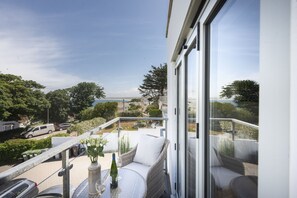 Een balkon met rieten meubels, een tafeltje en een bloemenvaas.