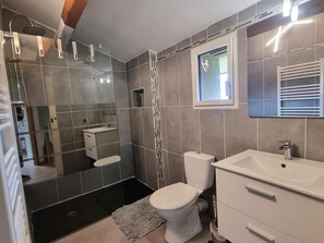 A modern bathroom with a shower, toilet, and sink.