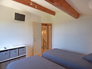A bedroom with two beds, a desk with storage bins, a door leading to a staircase, and a mounted television. - Renovated cottage with terrace and pets allowed in Saint-Chamond (Saint-Chamond)
