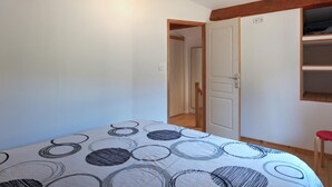 A bedroom with a bed, a wardrobe, and a door leading to another room.