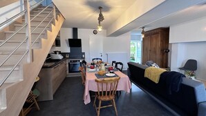 Een knus leefruimte met keuken, eethoek en een trap.