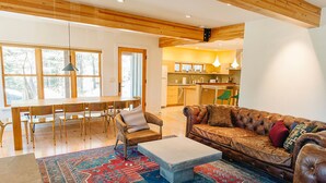 Ein geräumiges Wohnzimmer mit einer Ledersofa, einem Couchtisch und einer Essecke mit Holzmöbeln.