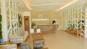 A modern hotel lobby with a reception desk, seating areas, and decorative elements. - Holiday Suites Puerto Princesa (Puerto Princesa)