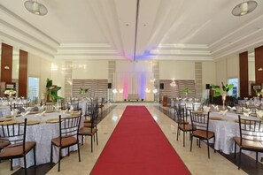 A banquet hall with round tables, chairs, a red carpet, and a stage with curtains. - Holiday Suites Puerto Princesa (Puerto Princesa)