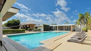 A swimming pool with a tiled deck, surrounded by modern buildings and palm trees. - Holiday Suites Puerto Princesa (Puerto Princesa)