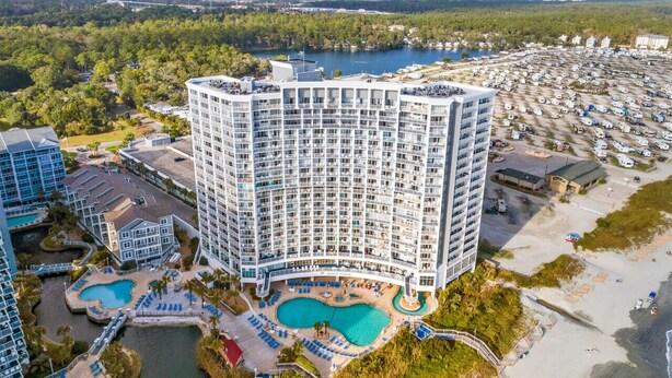 A high-rise hotel with multiple balconies, a central courtyard with a swimming pool, and a beach area. - Penthouse SeaWatch Ocean Front (Myrtle Beach)