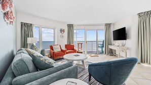 A modern living room with a sofa, two armchairs, a coffee table, and a TV. - Penthouse SeaWatch Ocean Front (Myrtle Beach)