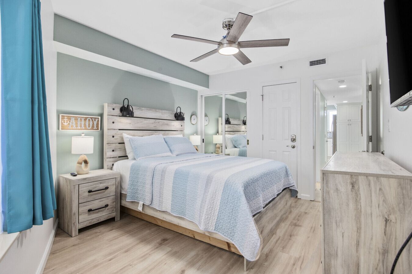 A bedroom with a bed, nightstands, a ceiling fan, a mirror, and a wardrobe.