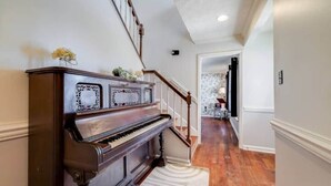 Um piano de cauda em um corredor com uma escada que leva a outro cômodo.