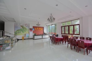 A spacious hotel lobby with a reception desk, a staircase, and a dining area with tables and chairs. - Jieya Hotel (Emeishan City)