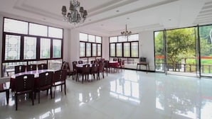 A spacious dining area with large windows, a chandelier, and a polished floor. - Jieya Hotel (Emeishan City)