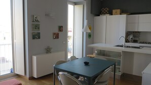 A compact kitchen with white cabinets, a built-in sink, and a dining area with a table and chairs. - "Nea Parthenope" apartment. (Napoli)