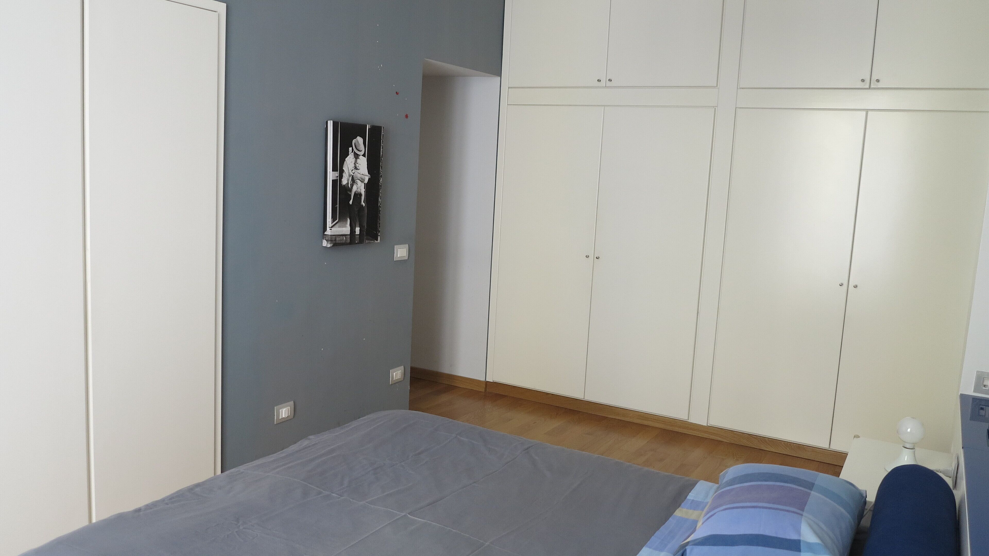 Un dormitorio con cama, armario y un cuadro en la pared.