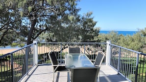 A deck with a table and chairs overlooking a beach and ocean. - Sandcastles Unit 8 - 2 bedroom Ocean Front Unit (Bargara)
