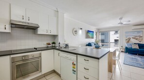 A modern kitchen with white cabinetry, a built-in oven, and a dishwasher. - Shoreline Apartments - Unit 10 (Bargara)