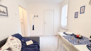 A room with a bed, a table with a plate and a glass, and a door in the background. - Maison De La Brodeuse by Ca-sa Check (Chioggia)