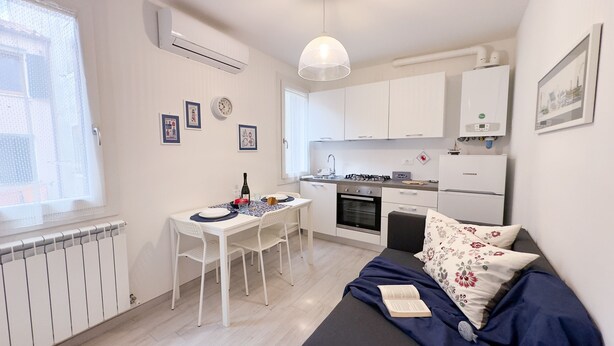 A compact living space with a kitchenette, a dining area, and a bed. - Maison De La Brodeuse by Ca-sa Check (Chioggia)
