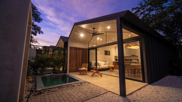 A modern house with a glass-enclosed living area, a pool, and a dining area. - Selvatico Tamarindo Villas (Tamarindo)