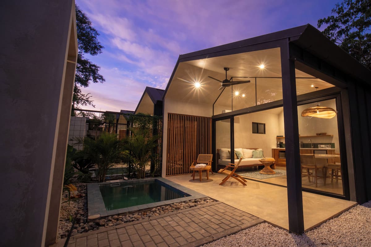 A modern house with a glass-enclosed living area, a pool, and a dining area.