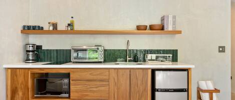 A compact kitchen with a built-in microwave, a toaster, and a refrigerator.