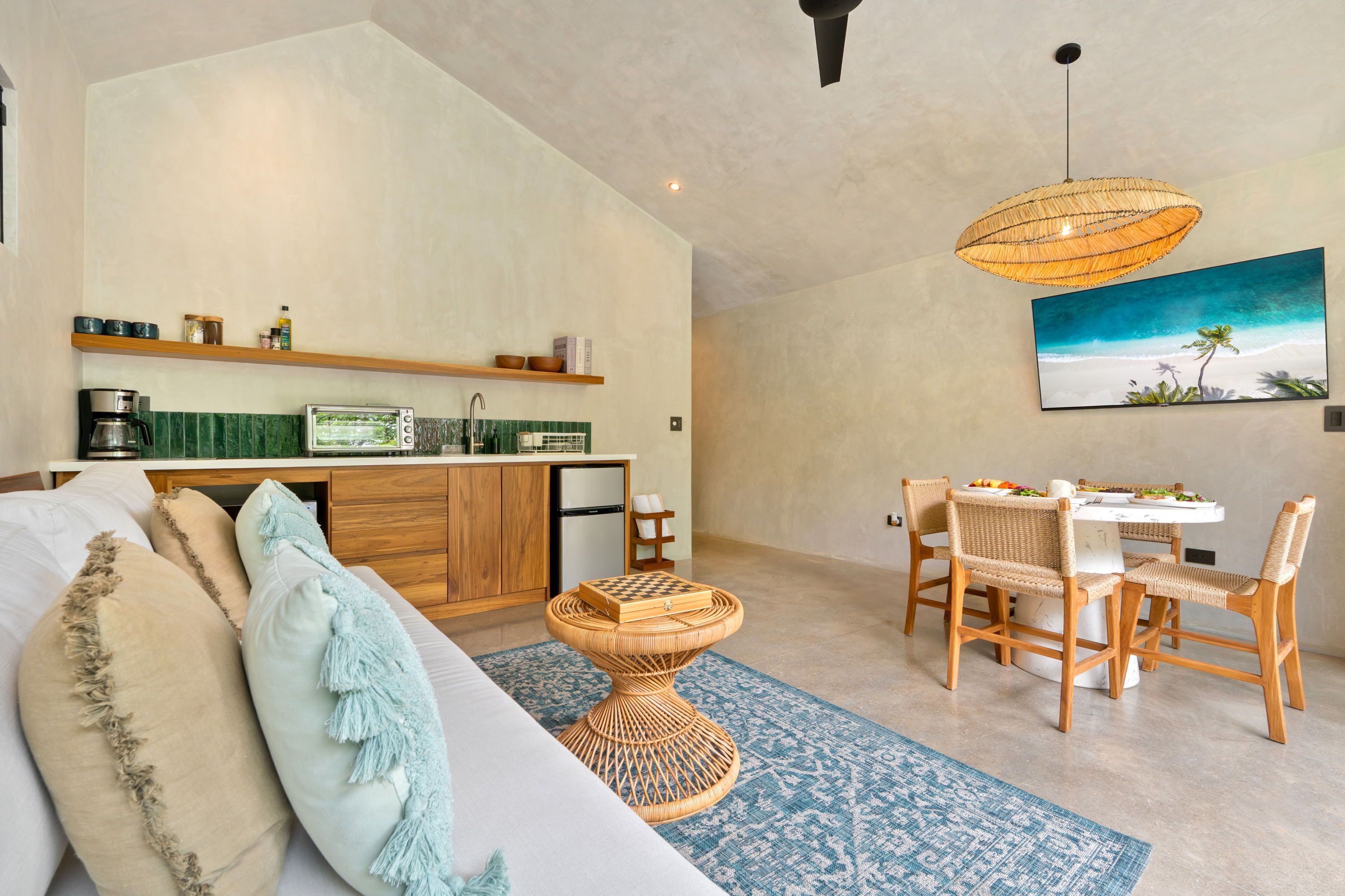 A modern living space with a kitchen, dining area, and a large window with a beach view.