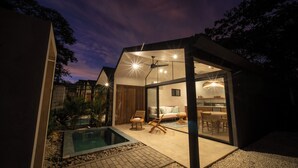 A modern house with a glass-enclosed living area, a pool, and a dining area. - Selvatico Tamarindo Villas (Tamarindo)