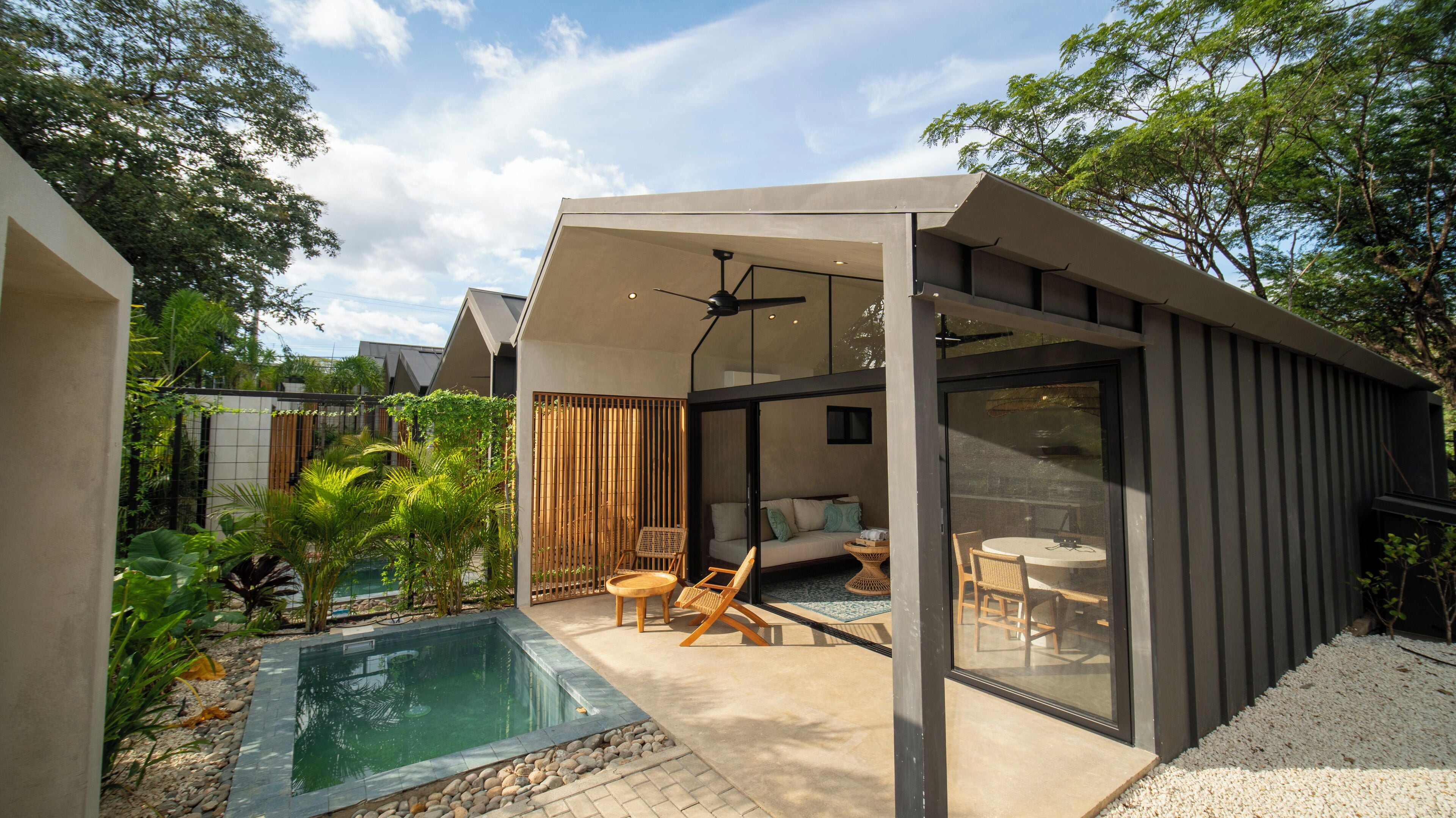 A modern outdoor living area with a pool, seating, and a glass-enclosed space.