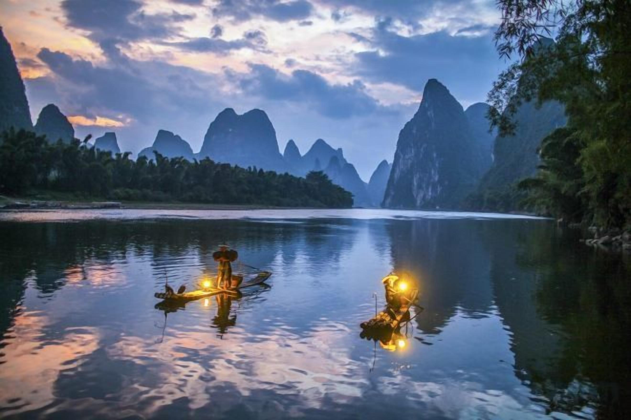 A calm river with boats and a mountainous landscape in the background.