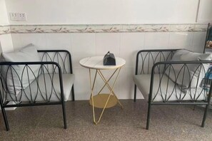 A room with two black metal chairs, a small round table with a gold base, and a white wall with a decorative border. - Qiqi Xiaozhan (Yangshuo Impression Liusanjie Scenic Area Shop) (Yangshuo)