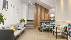 A modern interior with a grey sofa, a metal-framed chair, a staircase with wooden accents, and a wall decorated with framed pictures and a bulletin board. - Qiqi Xiaozhan (Yangshuo Impression Liusanjie Scenic Area Shop) (Yangshuo)