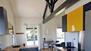 Una cocina moderna con una isla central, armarios negros y encimera de madera.