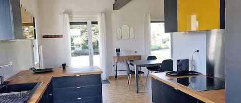 Una cocina moderna con una isla central, armarios negros y encimera de madera.