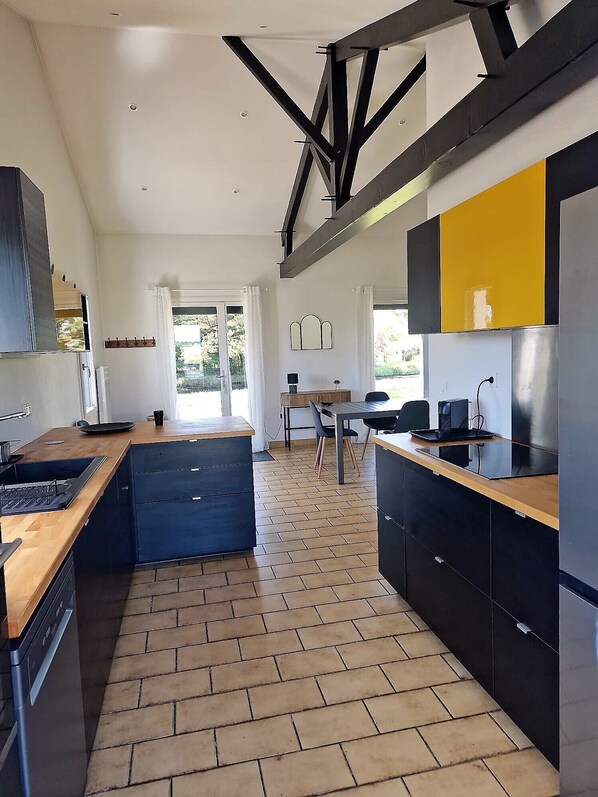 A modern kitchen with a central island, black cabinets, and a wooden countertop.