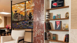 A modern interior with a seating area, a bookshelf with books and decorative items, and a decorative wall panel.
