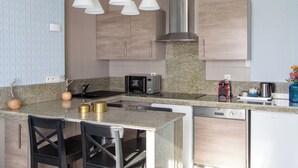 A modern kitchen with granite countertops, stainless steel appliances, and pendant lighting.