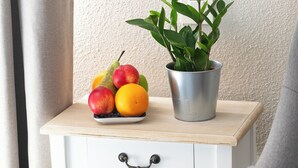 A small white bedside table with a drawer and a metal plant pot.
