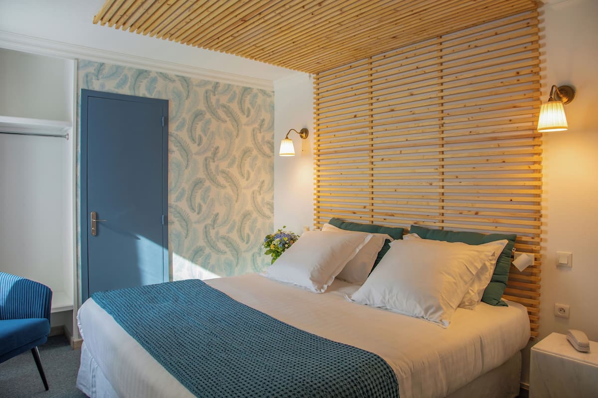 A bedroom with a bed, a nightstand, a chair, and a wooden slatted wall.