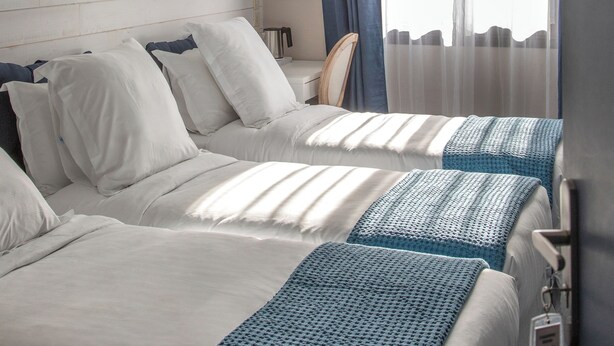 A hotel room with two beds, a desk, and a chair.
