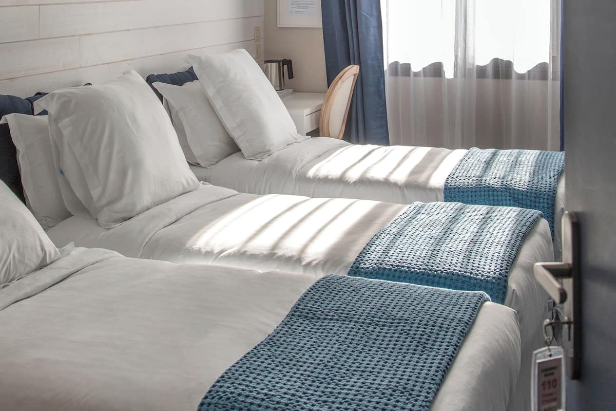 A hotel room with two beds, a desk, and a chair.
