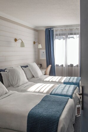 A hotel room with two beds, a desk, and a chair.